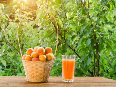 Bir hasır sepet ve yeşil bir arka plan üzerine suyu bir bardak kayısı