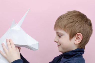 Beyaz kağıt tek boynuzlu at ve çocuk. Pembe bir arka plan.