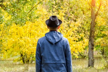 Siyah şapkalı bir adam ormanda ayakta duruyor. Sonbahar konsepti
