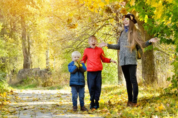 Mom and her sons toss the leaves. Autumn Park. — Stock Photo, Image