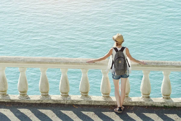 Chica con sombrero de pie en el balcón y mirando al mar — Foto de Stock
