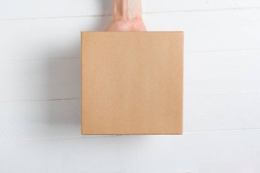Kadın elinde kare karton kutu. Üst görünüm, beyaz arkaplan