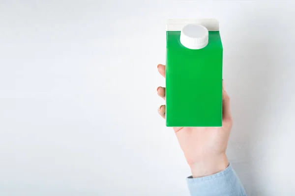 Zielone pudełko kartonowe lub opakowanie tetra z nakrętką w ręku kobiety. Białe tło — Zdjęcie stockowe