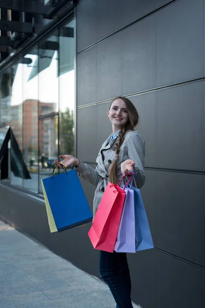 Šťastná mladá žena shopaholic s barevnými taškami v blízkosti obchoďáku. Procházka po ulici. — Stock fotografie