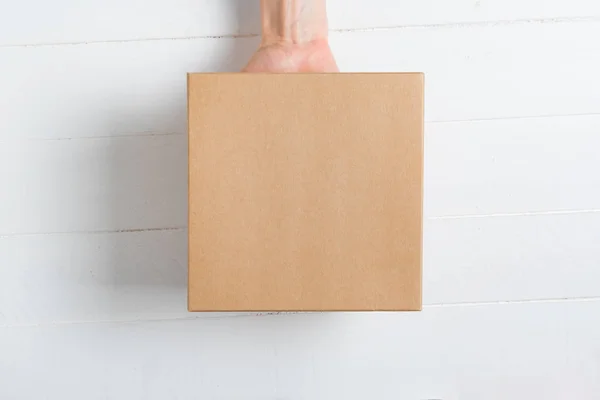 Square cardboard box in female hand. Top view, white background — Stock Photo, Image