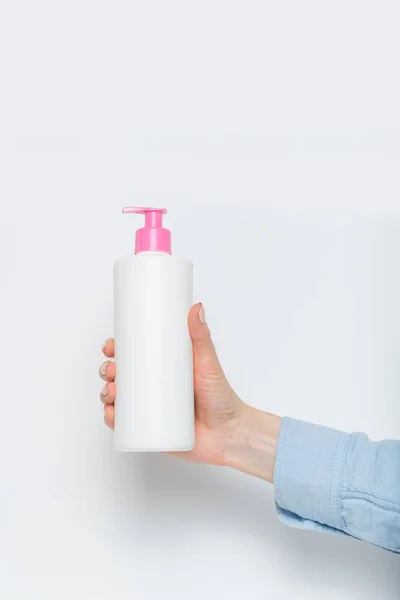 Μπουκαλάκι πλαστικό λευκό με αντλία στο γυναικείο χέρι. Λευκό φόντο — Φωτογραφία Αρχείου