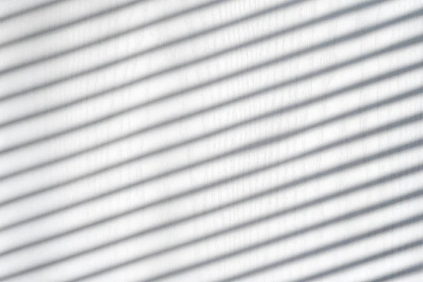 White wooden background with shadow from the blinds. Sunny day, interior