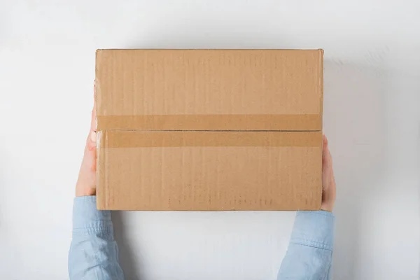 Велика квадратна картонна коробка в жіночих руках. Вид зверху, білий фон — стокове фото