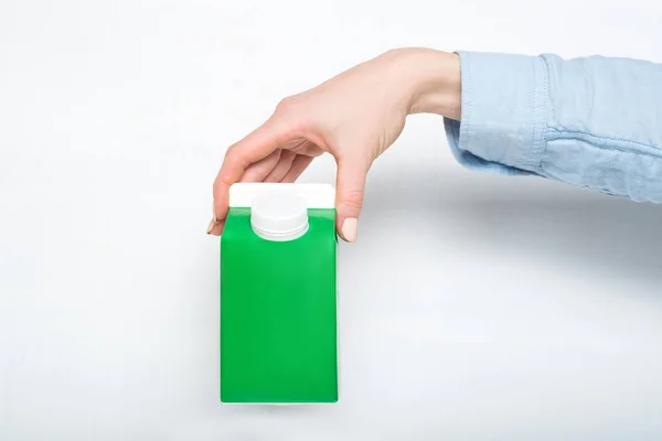 Caja de cartón verde o envase de tetra con una tapa en una mano femenina. Fondo blanco —  Fotos de Stock