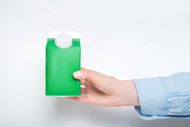 Yeşil karton kutu ya da elinde kadın eli olan tetra paketi. Beyaz arkaplan