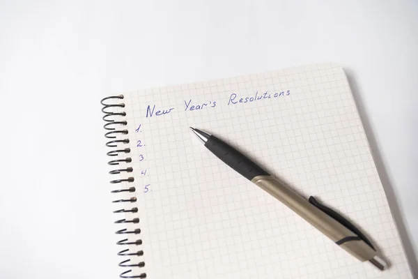 Phrase New Year's resolutions in a notebook, a pen. Close-up — Stock Photo, Image