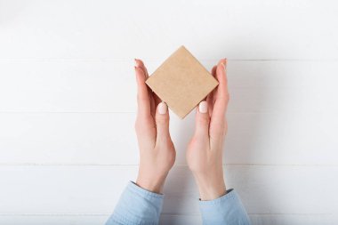 Kadın ellerinde küçük kare karton kutu. Üst görünüm, beyaz arkaplan