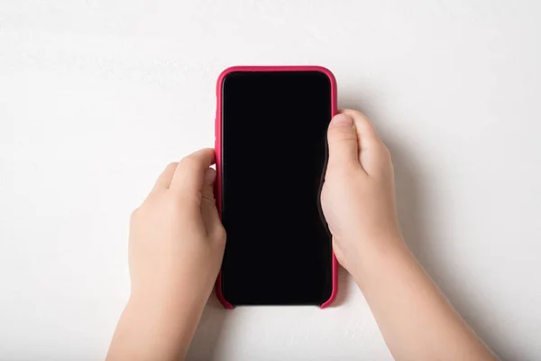 光の背景に子供の手の中にスマートフォン — ストック写真