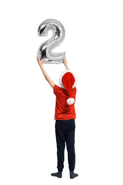 Il ragazzo con il cappello da Babbo Natale regge due cifre gonfiabili d'argento. Vista posteriore. Isolato su sfondo bianco . — Foto Stock