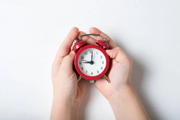 Reloj despertador rojo en las manos de los niños sobre un fondo blanco — Foto de Stock