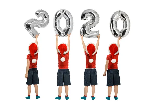 Liczba 2020 błyszczących balonów. Liczby w rękach chłopców w czerwonych kapeluszach. Białe tło — Zdjęcie stockowe