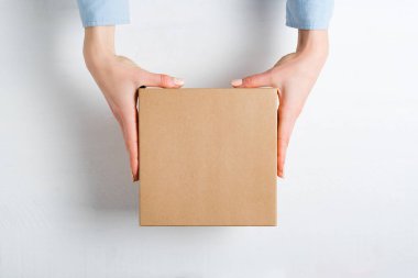 Kadın ellerinde kare karton kutu. Üst görünüm, beyaz arkaplan