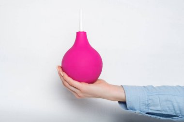 Kadın elinde büyük pembe lavman. Beyaz arka plan. Tıbbi öge