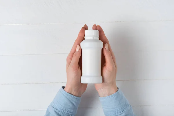 Fehér műanyag gyógyszeres palack egy női kézben. Fehér háttér — Stock Fotó