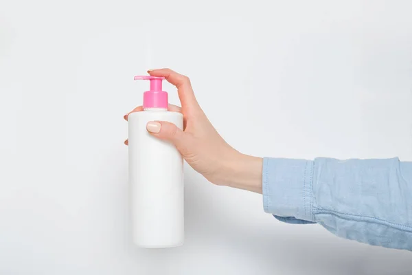 Fehér kozmetikai műanyag palack pumpával a női kézben. Fehér háttér — Stock Fotó