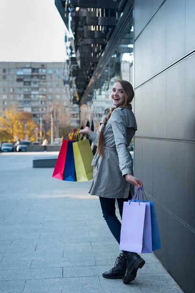 Šťastná mladá žena shopaholic s barevnými taškami v blízkosti obchoďáku. Procházka po ulici. — Stock fotografie