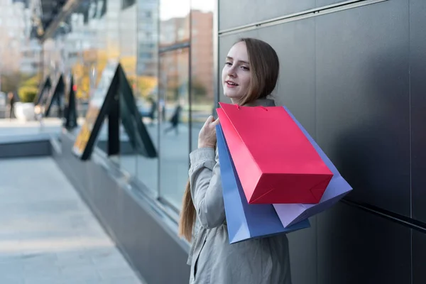 Mladá žena s barevnými taškami na ulici. Nákupní centrum na pozadí — Stock fotografie