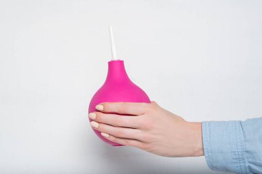 Kadın elinde büyük pembe lavman. Beyaz arka plan. Tıbbi öge