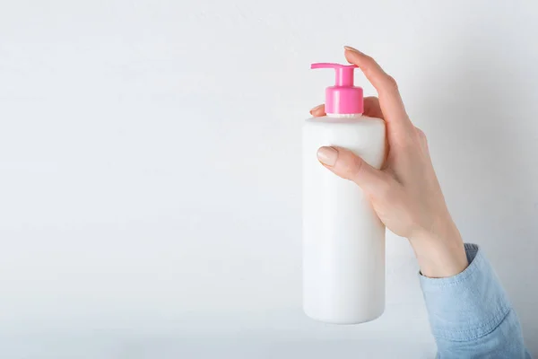 Fehér kozmetikai műanyag palack pumpával a női kézben. Fehér háttér — Stock Fotó