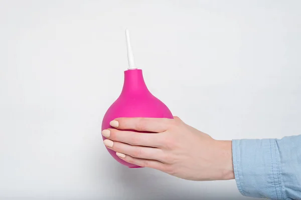 Nagy rózsaszín beöntés egy női kézben. Fehér háttér. Orvosi eszköz — Stock Fotó