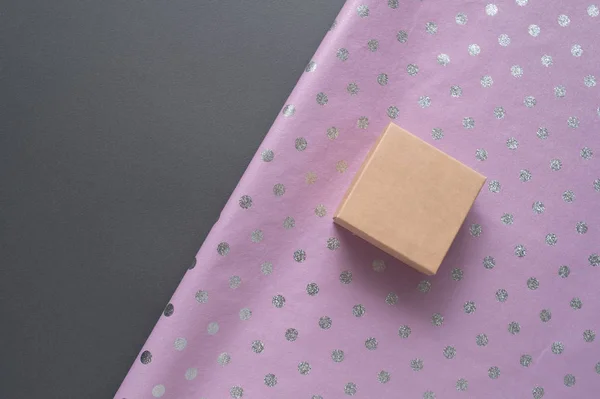 Маленькая картонная коробка и лиловая горошек упаковочная бумага. Серый стол. Подготовка к празднику — стоковое фото