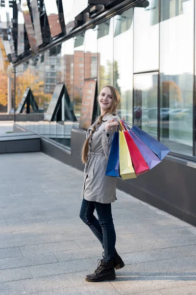 Šťastná mladá žena shopaholic s barevnými taškami v blízkosti obchoďáku. Procházka po ulici. — Stock fotografie