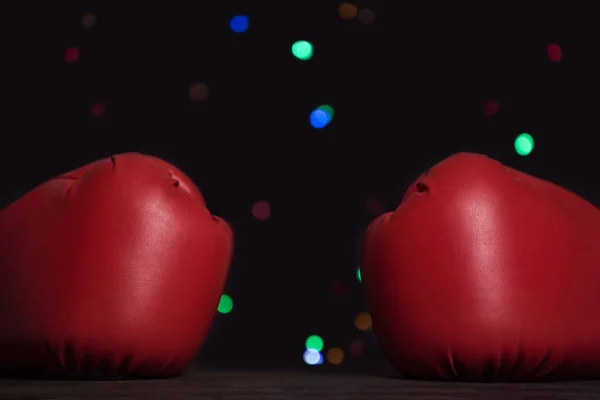 Pair of red boxing gloves, festive garland on background. Close up — Stock Photo, Image