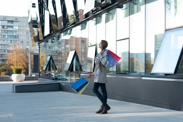 Feliz joven adicta a las compras con bolsas de colores cerca del centro comercial. Caminando por la calle . —  Fotos de Stock