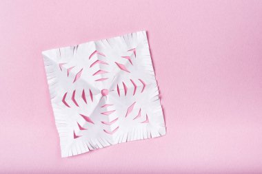 Pembe arka planda kağıttan kesilmiş kar tanesi. Çocukların yaratıcılığı.