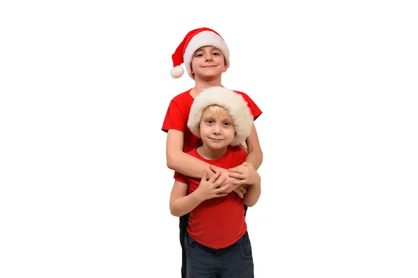 Twee leuke jongens met kerstmutsen knuffelen. Isolaat op wit — Stockfoto