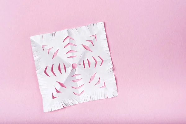 Copo de nieve cortado de papel sobre un fondo rosa. Creatividad infantil . —  Fotos de Stock
