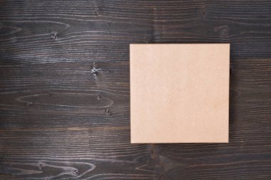 Kahverengi ahşap bir masanın üzerindeki kare el işi kutusu. Tam üstte