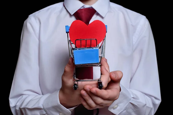 Boy houdt een metalen winkelwagentje met een hartvormige ansichtkaart binnenin. Sluiten. — Stockfoto