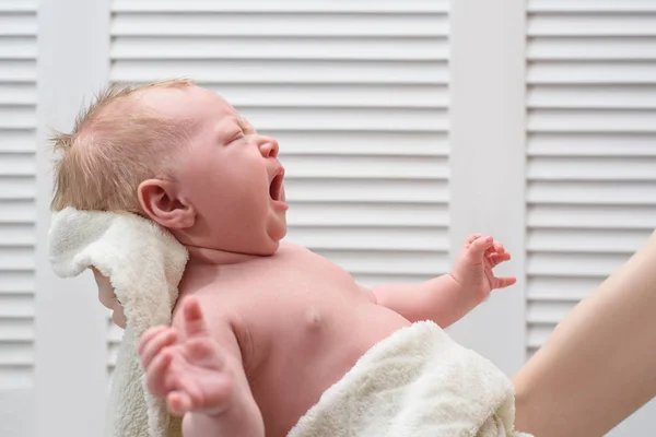 Gråtande blond bebis utan kläder. Spädbarn kolik. På händer, vit bakgrund. — Stockfoto