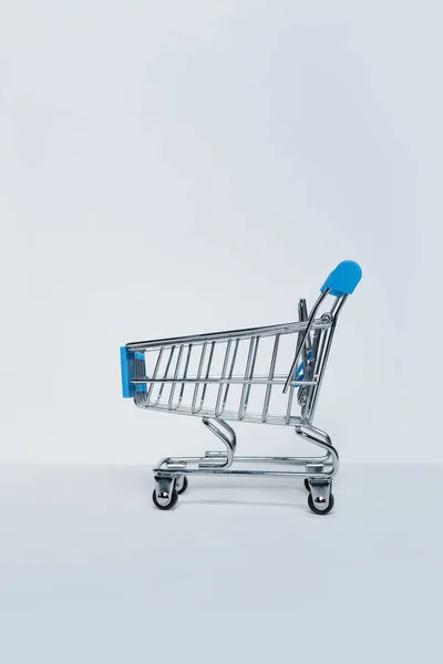 Small metal shopping trolley on a light background. Vertical frame — ストック写真