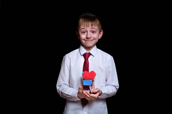 Усміхнений хлопчик тримає металевий візок з листівкою у формі серця всередині — стокове фото