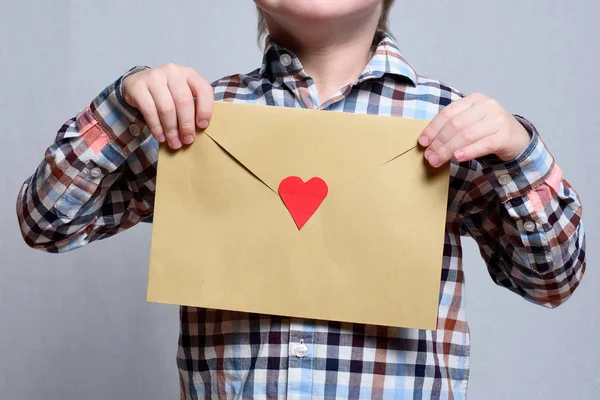 Grote envelop met een rood hart in kinderhanden. Close-up — Stockfoto