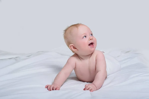 Sonriente bebé en su barriga. Mirando hacia arriba con expresión sorprendida. Fondo blanco —  Fotos de Stock