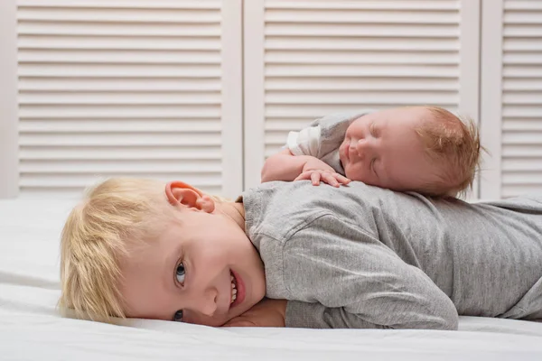 Niño rubio sonriente y hermanita recién nacida durmiendo boca arriba. Familia — Foto de Stock
