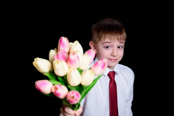 Cute boy in white shirt gives a bouquet of tulips. Isolate on black background — 스톡 사진