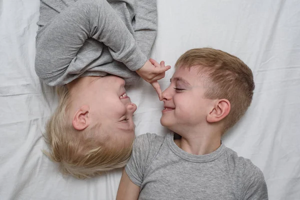 Dos chicos jugando acostados en la cama. Hermanos. Vista superior —  Fotos de Stock