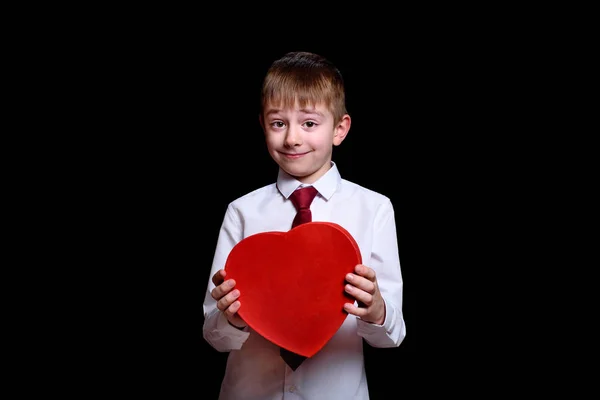 Blond jongetje met hartvormige rode doos op zwarte achtergrond. Liefde en familieconcept. Kopieerbasis. — Stockfoto