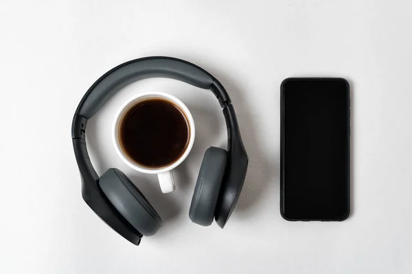 Wireless full-size headphones, smartphone and cup of coffee on white background. Directly above — Stock Photo, Image