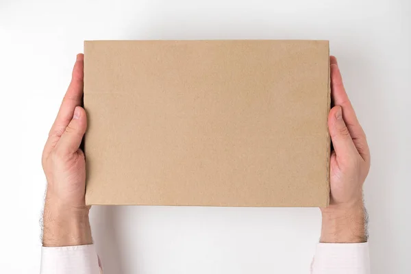 Dikdörtgen şeklindeki karton kutu beyaz arka planda erkeklerin eline geçer. Teslimat hizmeti konsepti. Üst görünüm