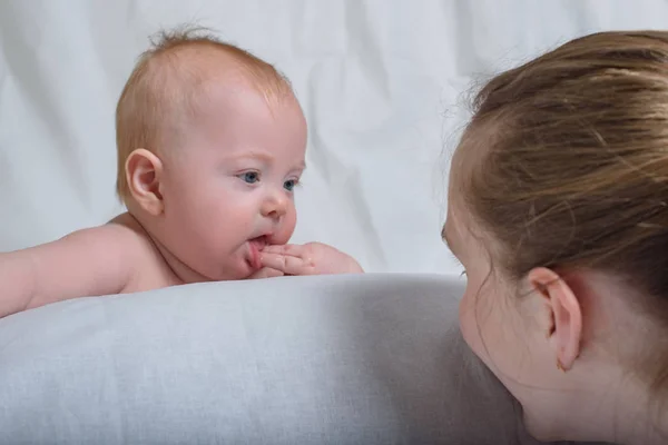 Mignon bébé regarde sa mère. Soeur et frère cadet. Le gamin suce les doigts . — Photo